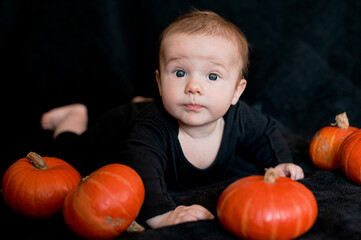 Fototapeta na wymiar Portrait of a child with pumpkins on a black background