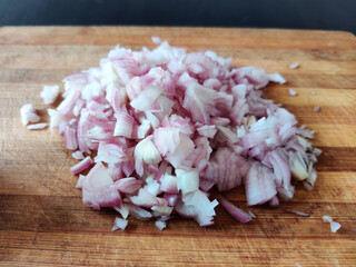 Close up of uncooked onion chopped into small cubes or pieces. Isolated on wooden board.