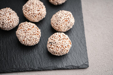 Vegetarian truffles from dates and white sesame on a slate Board close-up view from above