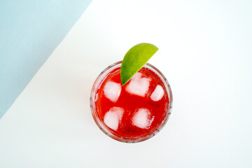 Red sparkling drink in the glass with ice and lime