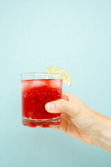 Hand holding Red sparkling drink in the glass