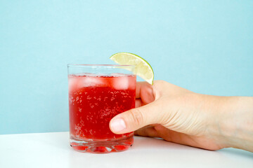 Hand holding Red sparkling drink in the glass