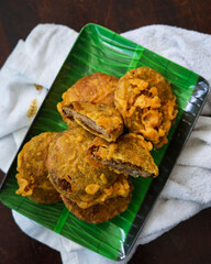 Kuih kasturi, a malaysian snack food made from green beans. Fried and served on a wooden plate.