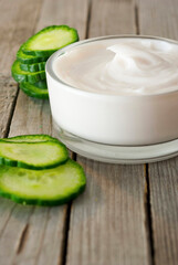 Obraz na płótnie Canvas Face cream and cucumber slices on old wooden table