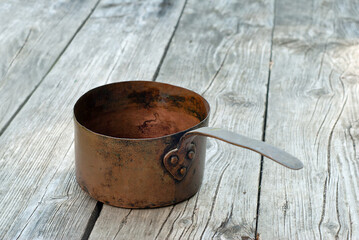 Antique rusty copper pots on wooden background