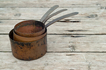 Antique rusty copper pots on wooden background