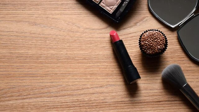 Lipstick and brigadier on the table. Makeup brush being put into the composition. Focus made on the brigadier.