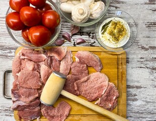 Pieces of chopped fresh raw pork meat on a cutting board with vegetables. The concept of proper nutrition, homemade food.