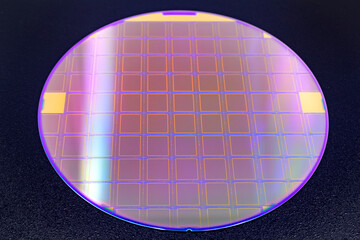 Silicon wafer with microchips on black background.