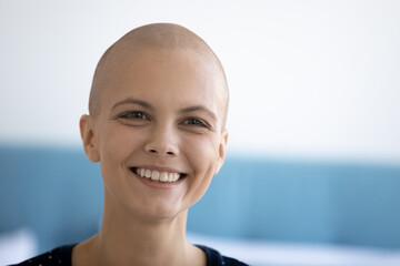 Close up of smiling millennial Caucasian hairless female patient struggling with cancer feel...