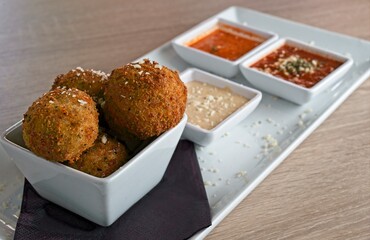 Risotto balls stuffed with mozzarella & deep fried. Served with marinara, fresh basil pesto & roasted red pepper purèe 
