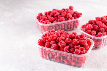 Fresh raspberries in a plastic tray on light background, copy space