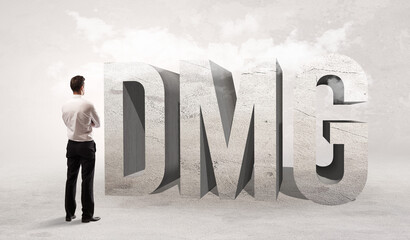 Rear view of a businessman standing in front of DMG abbreviation, attention making concept