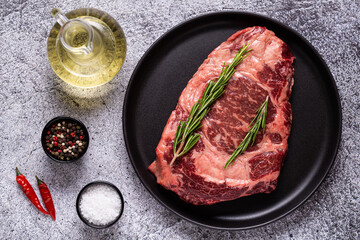 Fresh raw beef steak on black plate.
