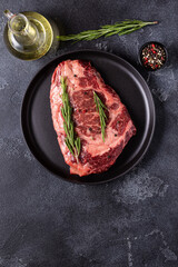 Fresh raw beef steak on black plate.