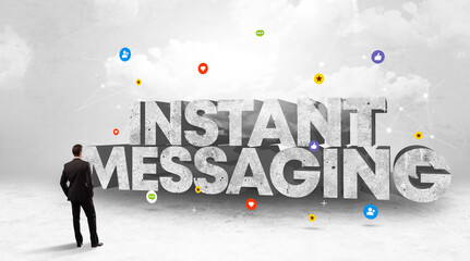 Young businessman standing in front of INSTANT MESSAGING inscription, social media concept