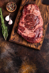 Fresh raw beef steak on a cutting wooden board.