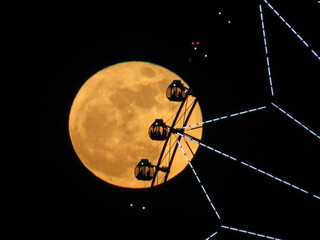 大きな満月と重なる観覧車のシルエット