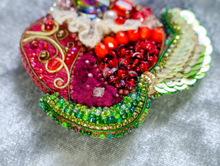 Decorative red apple made of beads, sequins and lace on a gray background