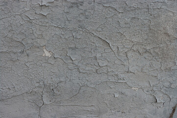 old grey plaster is peeling from the wall background texture