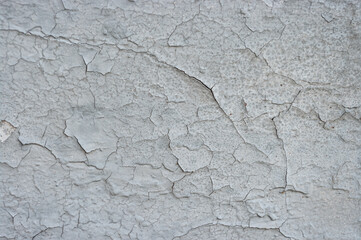 old grey plaster is peeling from the wall background texture