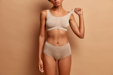 Femine beauty lines concept. Slim woman with dark skin flat stomach wears high waist panties and...