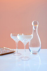  glass decanter, elegant glasses with cocktail and ice on beige background. Alcohol, water, party, hotel, bar concept