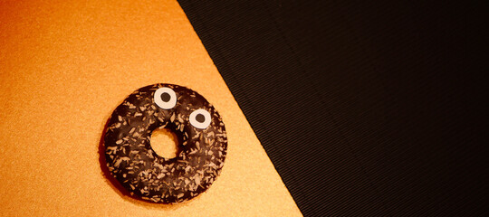 Shocked Chocolate frosting donut with eyes. Halloween party symbols. Spooky food banner. Copy...
