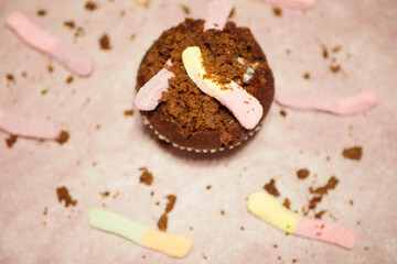 Chocolate muffin with worms. Scary food. Halloween party desserts. Top view