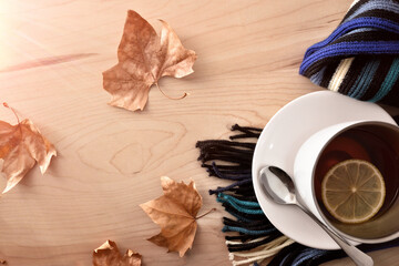 Cup with tea with lemon on  scarf on wooden table