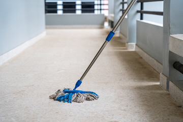 The blue mop was placed to wait to clean the dirty and dusty house floor.