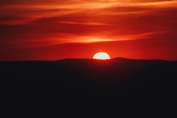 Beautiful image of the sun setting behind the mountains on a hot summer day