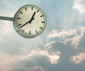 Circular white clock on sky and cloud background.