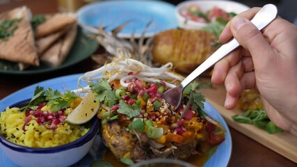 Fork picking thai curry served in a pineapple. Healthy oriental plant-based cuisine 