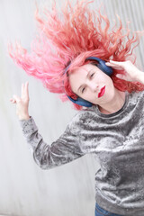 mujer d epelo color rosa con auriculares grandes y labios rojos bailando y moviendo el pelo - obrazy, fototapety, plakaty