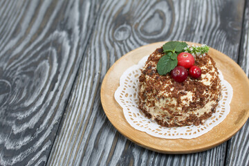 Sponge cake with butter cream. Decorated with cranberries and mint. Against the background of brushed pine boards.