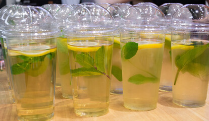Lots of clear plastic cups with a lid and lemonade, or green tea with lemon and mint