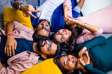 four indian friends lying down on the floor with pillows