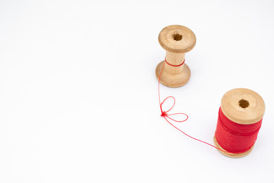 Two Wooden Spools Of Thread. One Is Full, The Other Almost Empty, Connected By A Single Thread. Togetherness As A Concept, No People, Without People