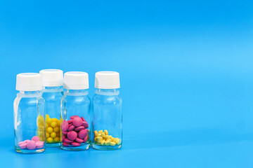 pills in glass bottles on blue background with copy space