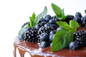 Cake with chocolate, decorated with backberries, blueberries, mint leaves.