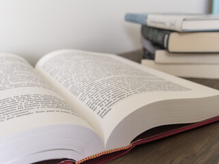 Close up of an open book and stack of books on the blurred background