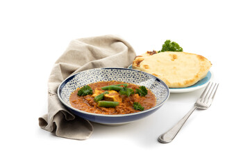 a blue bowl of Indian buttered chicken with a plate of naan bread on a white background