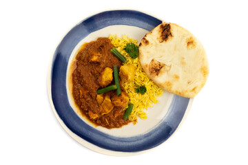 overhead view of a blue plate of Indian buttered chicken with green beans and curry rice and naan bread isolated on a white background