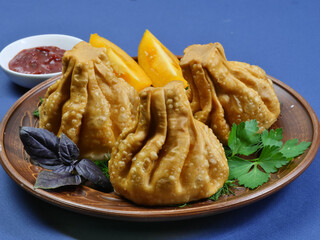 Khinkali Fried with lamb and herbs on a brown platter. Close up. Georgian cuisine.
