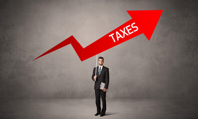 Obraz premium Young business person in casual holding road sign with TAXES inscription, business direction concept