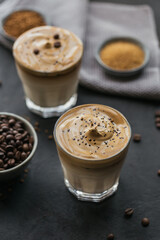 Glass of Iced Dalgona Coffee, trendy fluffy creamy whipped coffee and milk on black background.