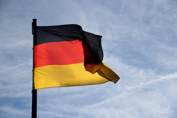 Fototapeta premium flag of the federal republic of Germany freely flutters in the wind against a blue sky, , concept of tourism, economy, politics, emigration, business