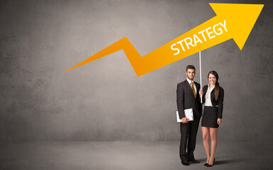 Fototapeta premium Young business person in casual holding road sign with STRATEGY inscription, business direction concept