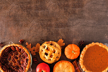 Selection of homemade autumn pies. Pecan, pumpkin and apple. Top view bottom border on a dark stone...